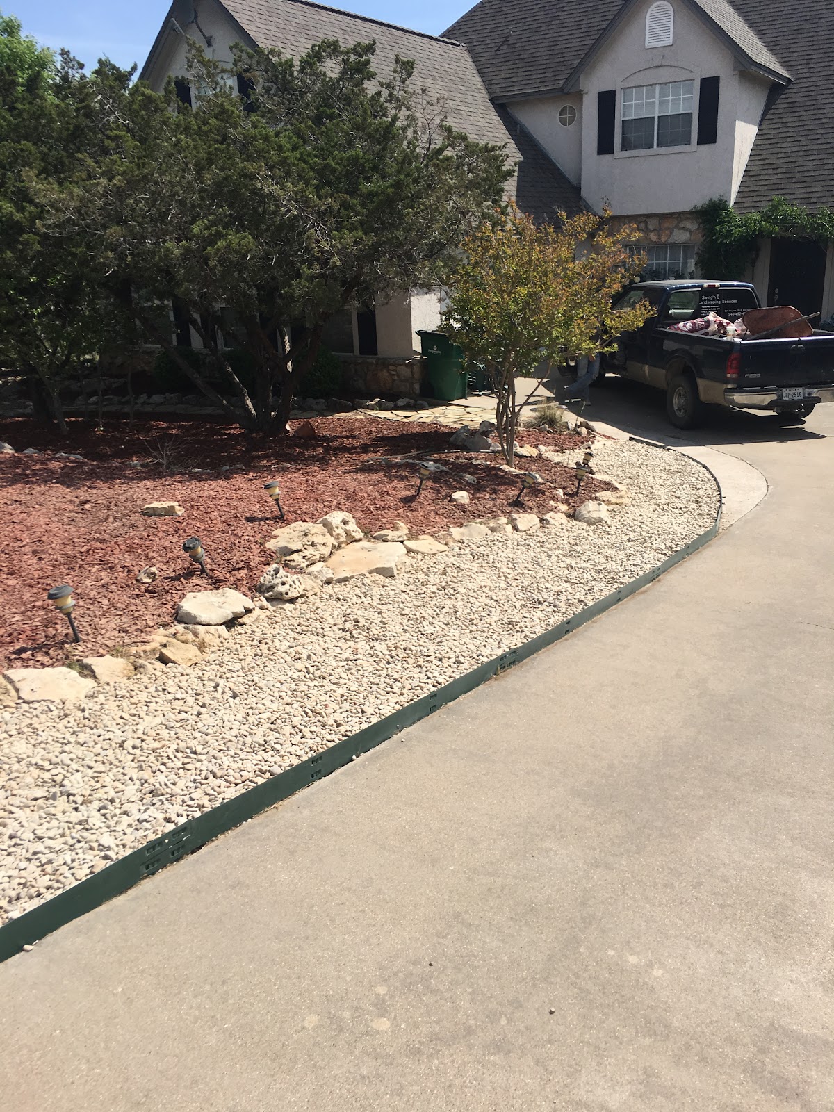 Completed landscaping with rock beds, mulch, and shrubs