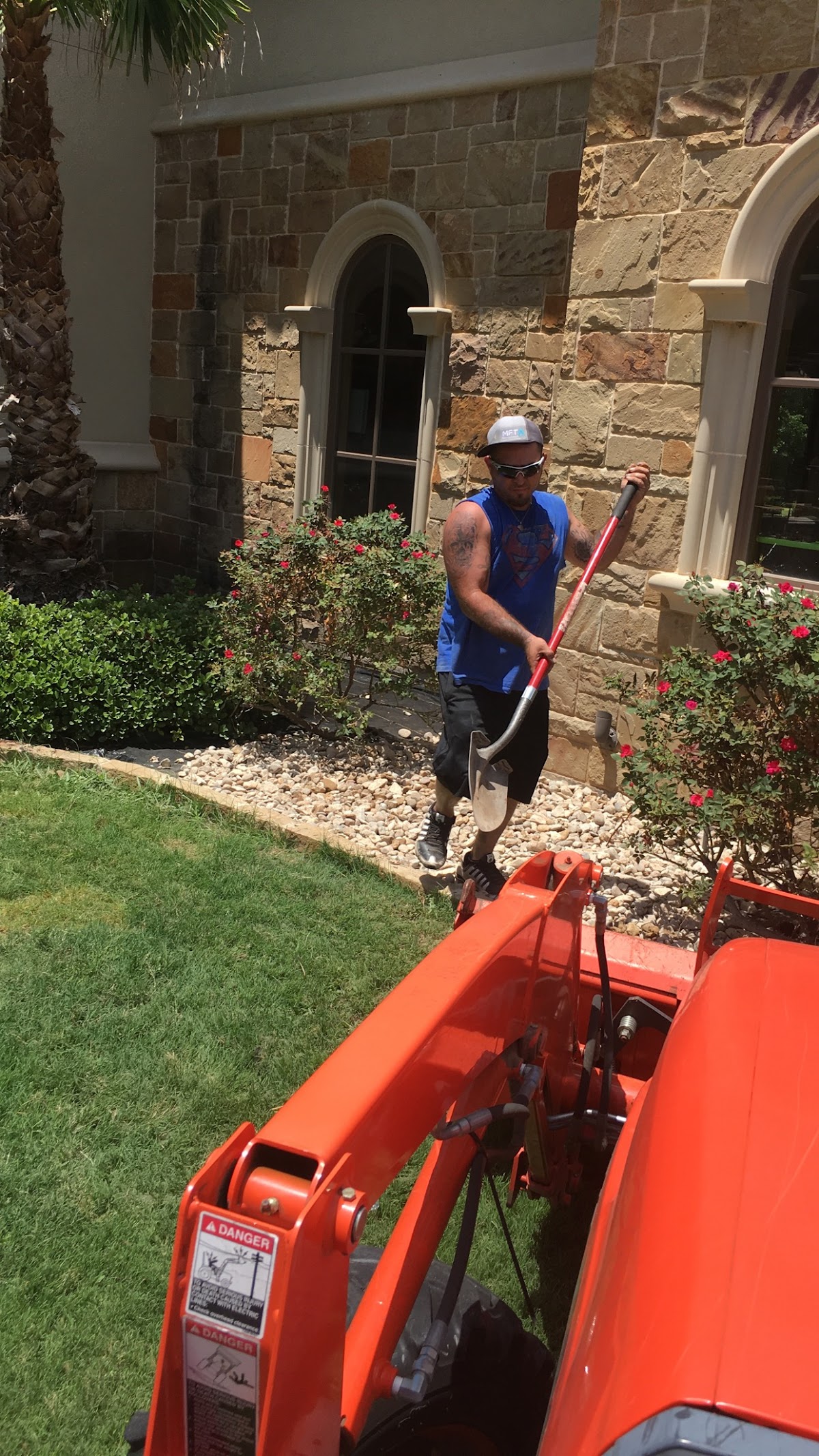 Worker operating stump grinder near stone mansion